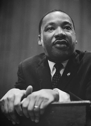 Martin Luther King leaning on a lectern. Deuts...